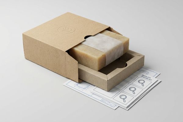 An open kraft paper box reveals a natural soap bar wrapped in translucent paper, with a Quality Checklist document below.