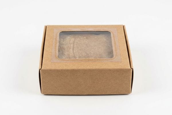 Brown Kraft paperboard box with a clear viewing window revealing a light brown, textured product inside, ideal for soap packaging.