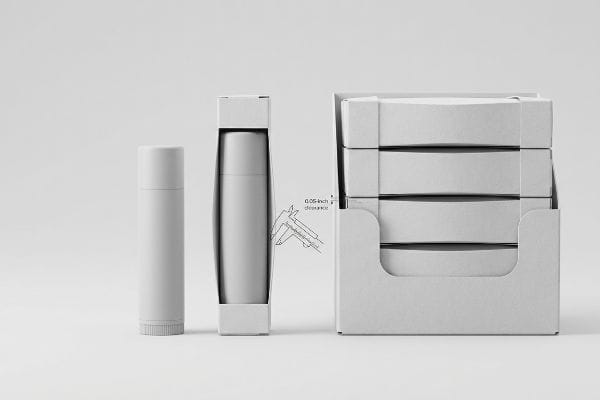 White lip balm packaging: tube, boxed unit with caliper measuring 0.05-inch clearance, and display tray of four boxes.