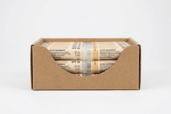 SPF 30 Lip Balm Tray Kraft cardboard retail-ready tray displays numerous lip balm tubes, clearly showing "Active Ingredients", "SPF 30", and "Net Wt. 0.15 Oz (4.25g)" on their labels.