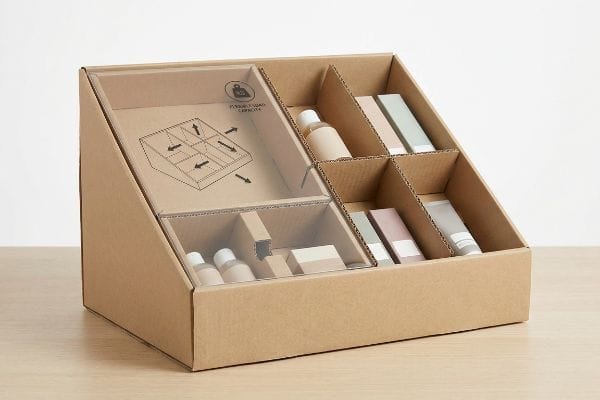 Modular Retail Display Box A modular corrugated retail display box with internal dividers, showcasing various cosmetic bottles and product packaging, featuring a "Possible Load Capacity" diagram.