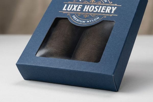 Luxe Hosiery Nylon Box A dark blue hosiery box with a window displays two rolled premium nylon stockings, featuring 'Luxe Hosiery' in gold foil.