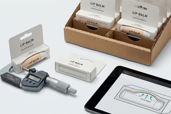Lip Balm Packaging Measurement Digital micrometer measures Lip Balm Counter Display packaging at 13.00, with a tablet showing a micro-bulge diagram and a display tray.
