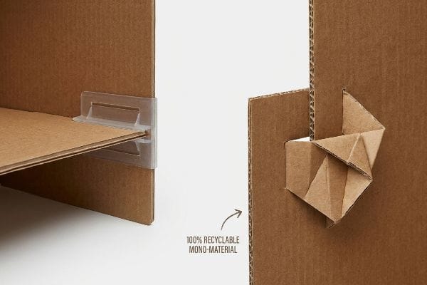Paper Lock vs Plastic Clear plastic shelf clip securing a corrugated board shelf next to an origami-style paper lock labeled "100% Recyclable Mono-Material".