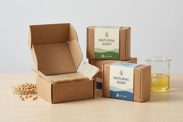 Natural Soap Soy Packaging E-flute corrugated boxes of Natural Soap with Soy Ink labels, an open box revealing soap, soybeans, and soy oil.
