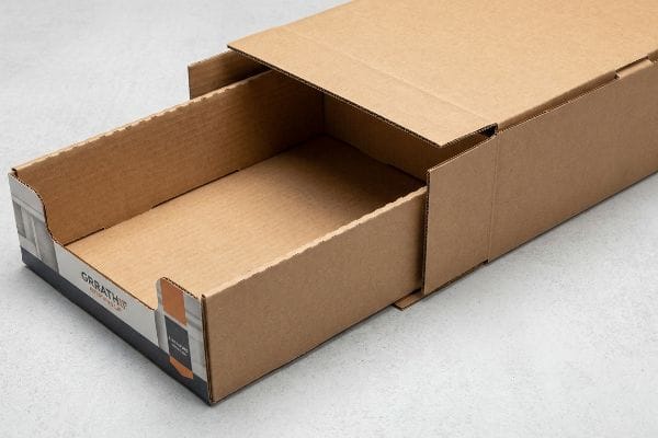 Brown corrugated cardboard nested shipping system with an empty Grrathis inner retail tray partially pulled from its master carton, showcasing geometric offset.