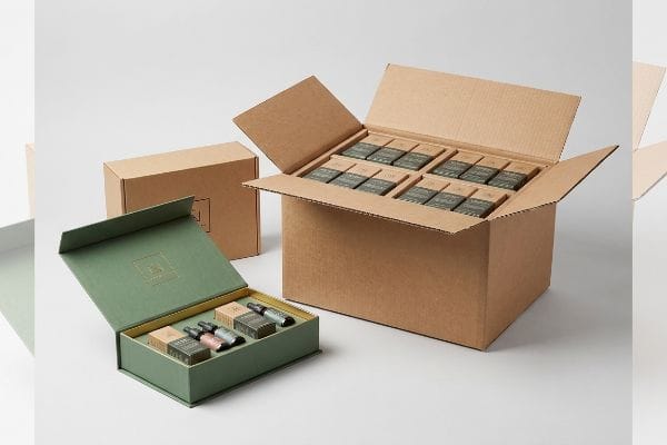 حلول شحن صناديق الهدايا علبة هدايا خضراء صلبة تحتوي على زجاجات صبغة CBD، بجوار كرتونة شحن رئيسية مفتوحة من الورق المقوى المموج تحتوي على علب بيع بالتجزئة.