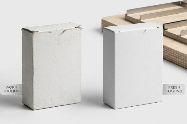 Tooling Quality Comparison Rough, discolored edges on a white tuck box from Worn Tooling contrast sharply with the pristine, razor-sharp edges of a box made with Fresh Tooling.