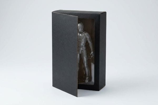Action Figure Unboxing Reveal Partially open black corrugated action figure packaging reveals a translucent grey articulated figure through a clear window.