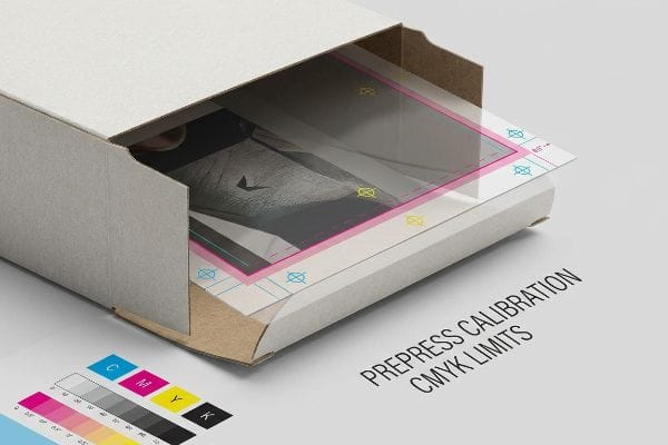 A printed sheet with Prepress Calibration CMYK Limits and registration marks slides into an open cardboard box, alongside a CMYK color chart.