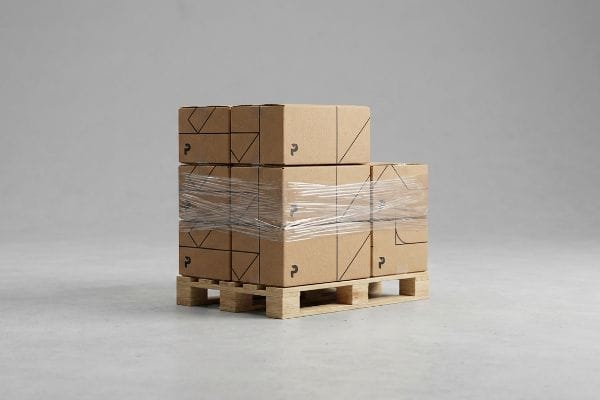A pallet of custom brown cardboard boxes, shrink-wrapped for transit, featuring a black 'P' logo and geometric designs.