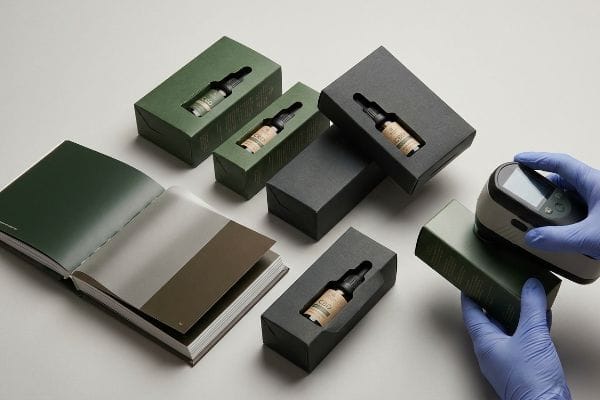 Farbprüfung der CBD-Verpackung Ein Spektralphotometer misst die Farbe von mattgrünen CBD-Verpackungskartons mit Tropfflaschen und gewährleistet so die Farbgenauigkeit für Soft-Touch-Oberflächen.