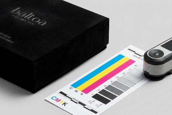 Black Baltoa Cosmetic box, Soft-Touch Finish, CMYK color chart, and spectrophotometer for ink density measurement.