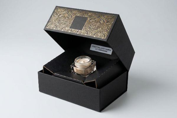 Black luxury cosmetic packaging box open, revealing a glass cream jar and a label reading "Structural Audit Sample ECT Downgrade" with gold foil.