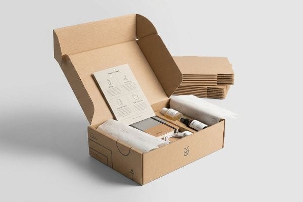 Brown kraft subscription box open, revealing 'What's Inside' card, small bottles, and tissue paper for a premium unboxing.