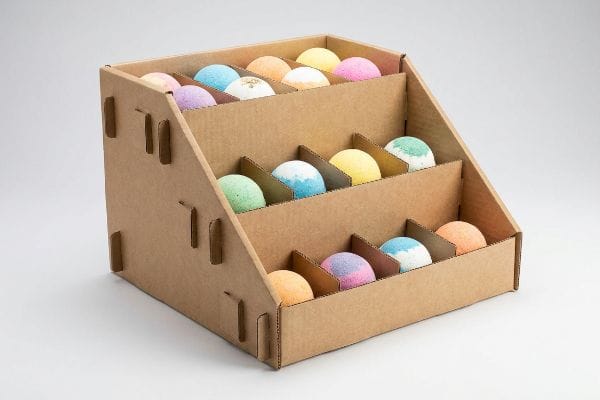 Bath Bomb Display Box A three-tiered corrugated cardboard display merchandiser showcases colorful bath bombs, ideal for wholesale retail point-of-purchase.