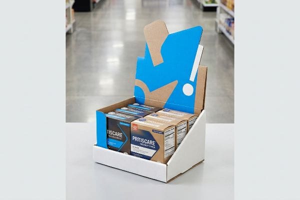 Una caja expositora de cartón blanca y marrón para la venta al por menor, que presenta los productos Tiscare y Pritiscare Go-Dose, con un panel trasero gráfico azul y blanco.