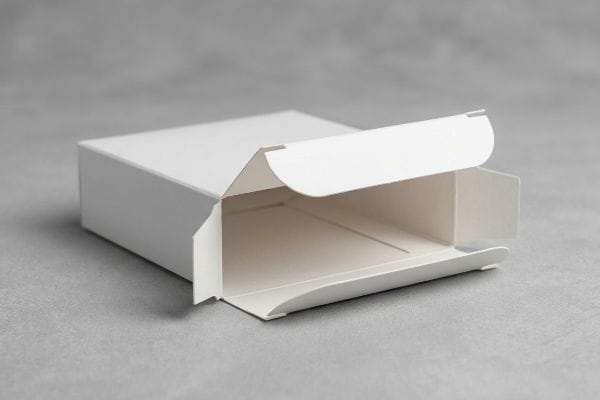 Open White Tuck Box White paperboard tuck box with its top flap open, revealing the friction-lock mechanism and empty interior, on a grey surface.