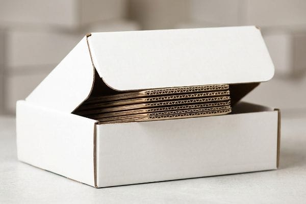 Corrugated Box Flutes Stack An open white corrugated box displays a stack of unassembled fluted cardboard sheets, revealing the internal structure.