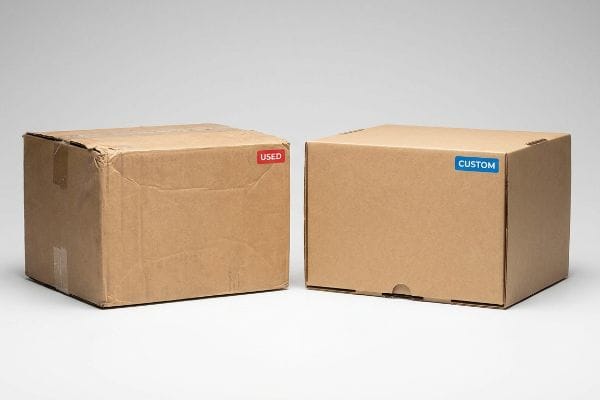 Used vs Custom Boxes Brown corrugated cardboard box with a red 'Used' label beside a new box with a blue 'Custom' label.
