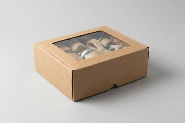 Craft Box Window Packaging Brown Kraft paperboard box with a flexible window showcasing artisanal products in glass jars tied with twine.