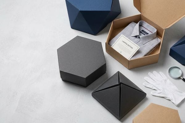 ユニークなシャツボックスパッケージ 折り畳まれた柄入りのシャツと「限定版」カードが入った、クラフト紙製の六角形のシャツボックス。ユニークな形状のパッケージも付属しています。.