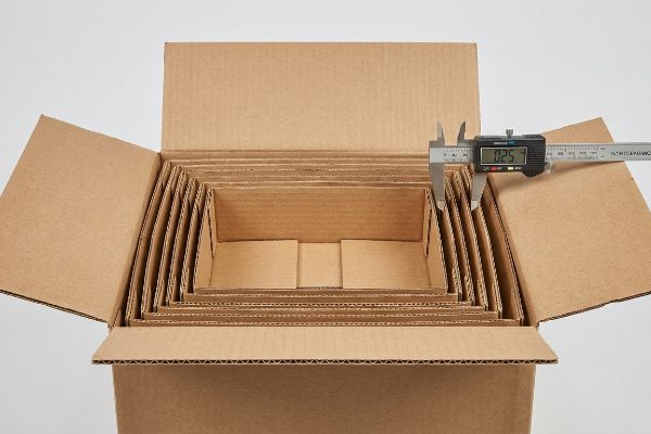 Wellpappkarton Offset 0,25 Zoll Ineinander gestapelte Wellpappkartons, ein digitaler Messschieber misst einen Versatz von 0,25 Zoll für die Verpackung.