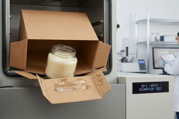 Candle Packaging Migration Test Kraft box with candle jar undergoing a 350C (950F) Migration Test, showing fragrance solvent migration damage on the bottom flaps.
