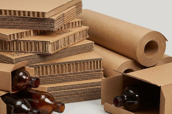 32 Ect Corrugated Kraft Rolls Packaging materials including stacks of 32 ECT corrugated board, rolls of virgin kraft paper, and amber bottles in boxes.