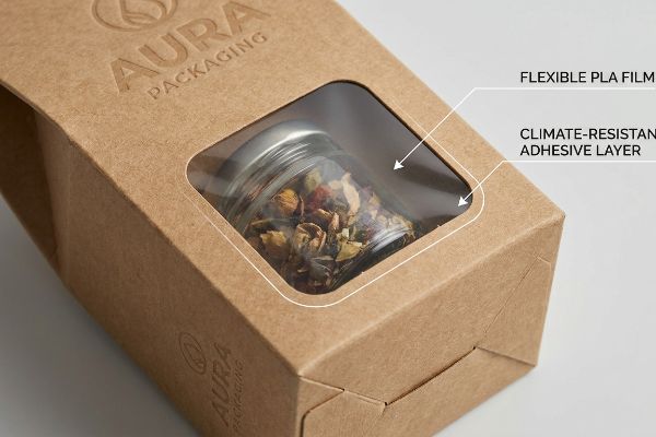 Flexible Pla Film Adhesive Brown kraft paperboard box with a Flexible PLA Film window and Climate-Resistant Adhesive Layer, embossed Aura Packaging logo, revealing a jar.