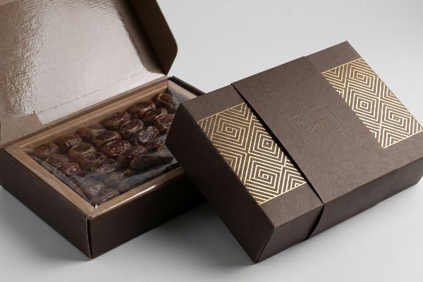 Premium Dates Gold Foil Packaging Dark brown dates fruit packaging with gold geometric foil and embossed Premium Dates text, alongside an open box revealing dates in a clear tray.